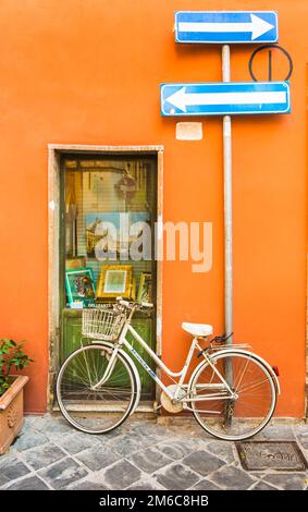 Frecce indicatrici del percorso, bicicletta bianca e pittura nella vetrina di una galleria d'arte Foto Stock