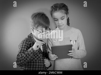 Stile retrò - i bambini del passato guardano un tablet. Ritorno al futuro Foto Stock