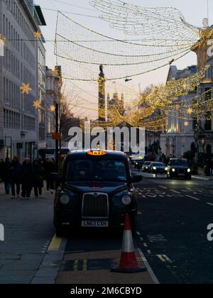 Spiriti di Natale appesi su Regent Street St James. Waterloo Place and Houses of Parliament dietro Londra, Inghilterra. Foto Stock