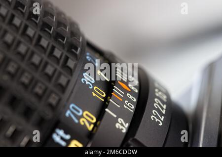 Primo piano di un cilindro della lente nero con linee pulite e nitide, nonché numeri gialli, blu e bianchi. Ripresa ad angolo verso l'alto, profondità di campo ridotta. Foto Stock