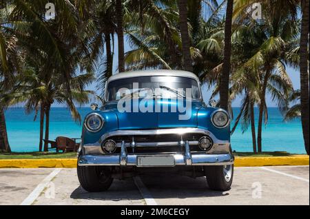 Auto classica blu americano con tetto bianco parcheggiato sotto le palme a Varadero Cuba - Serie Cuba Foto Stock