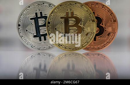 Primo piano di Bitcoins, bitcoin oro, bitcoin argento e bitcoin bronzo con sfondo sfocato delle bandiere del mondo. riflessione di Foto Stock