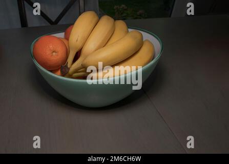 Banane e arance in una grande ciotola sul tavolo da pranzo per l'uso quotidiano Foto Stock