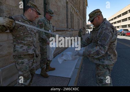 STATI UNITI Benjamin Neumon, a sinistra, un ufficiale di ingegnere assegnato alle forze armate quartier generali - Connecticut, Connecticut Army National Guard, utilizza un raccoglitore di rifiuti per mettere i rifiuti in un sacchetto di rifiuti che è tenuto aperto dagli Stati Uniti Seth Mastrocola, a destra, un ufficiale di operazioni mediche assegnato alle forze congiunte Quartier generale - Connecticut, Connecticut Guardia Nazionale dell'esercito presso il Governatore William A. o' Neill Armory, Hartford, Connecticut, 22 aprile 2022. In onore della Giornata della Terra, i soldati della Guardia Nazionale dell'Esercito del Connecticut, dal rango di privato fino al generale brigadiere, lavorarono insieme per c Foto Stock