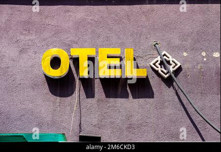 Colorato giallo OTEL segno su una parete di un edificio in fase di ristrutturazione, con tubi che sporgono. Decorazioni islamiche Foto Stock