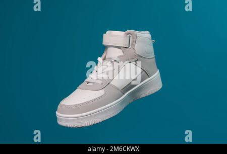 Una nuova sneaker bianca su sfondo blu Foto Stock