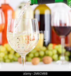 Vino versando da bottiglia vino bicchiere vino bianco quadrato bianco bottiglia di vino Foto Stock