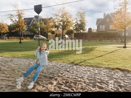 Divertimento autunnale all'aperto. Ragazza adolescente in sella a un bungee appeso sul parco giochi Foto Stock