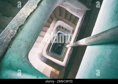 Pericoloso blu e bianco scale a spirale in un edificio usurati. Foto Stock