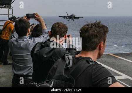 PHILIPPINE SEA (23 aprile 2022) membri di media internazionali esercenti di voli cinematografici a bordo della portaerei di classe Nimitz USS Abraham Lincoln (CVN 72). Abraham Lincoln Strike Group è in fase di implementazione pianificata nell'area delle operazioni della flotta 7th degli Stati Uniti per migliorare l'interoperabilità attraverso alleanze e partnership e al tempo stesso fungere da forza di risposta pronta a sostegno di una regione indomPacifico libera e aperta. Foto Stock