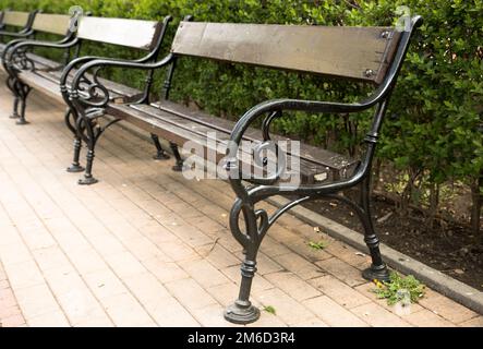 Una fila di legno e metallo panchine lungo un marciapiede in un parco Foto Stock