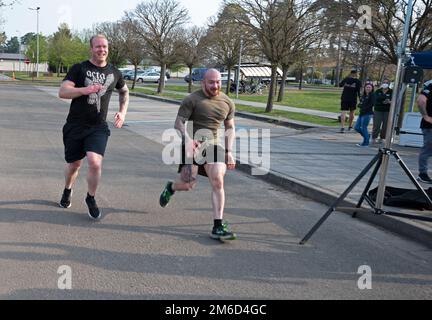 Due corridori attraversano il traguardo al Memorial Pat Tillman Run presso la base aerea di Ramstein, Germania, 23 aprile 2022. I partecipanti sono venuti a prendere parte alla corsa di 4,2 miglia come un modo per onorare i risultati e la vita di Pat Tillman, un ex giocatore della National Football League che ha aderito agli Stati Uniti Esercito di essere con il fratello dopo gli attacchi del 11 settembre. Foto Stock