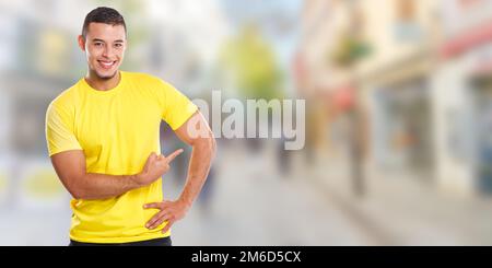 Giovane uomo latino che mostra puntando città di marketing annuncio pubblicità persone copyspace copia banner spazio Foto Stock
