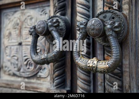 Bella porta in legno con ornamenti in ferro in una chiesa ortodossa, particolare di vecchio knockker sul do Foto Stock