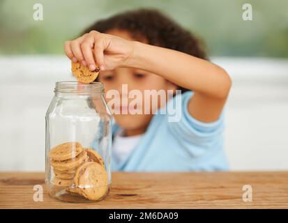 MMM, tanti cookie solo per me. Un ragazzo carino che afferra un biscotto dal vasetto del biscotto. Foto Stock