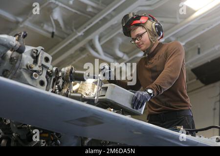 MARE DELLE FILIPPINE (24 aprile 2022) il tecnico dell'elettronica aeronautica Airman Robert Hall, di Charlotte, N.C., effettua la manutenzione su un elicottero MH-60s Sea Hawk, assegnato ai “Chargers” di Helicopter Sea Combat Squadron (HSC) 14, a bordo della portaerei di classe Nimitz USS Abraham Lincoln (CVN 72). Abraham Lincoln Strike Group è in fase di implementazione pianificata nell'area delle operazioni della flotta 7th degli Stati Uniti per migliorare l'interoperabilità attraverso alleanze e partnership e al tempo stesso fungere da forza di risposta pronta a sostegno di una regione indomPacifico libera e aperta. Foto Stock