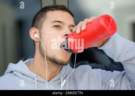 Acqua potabile sport allenamento fitness giovane uomo latino inverno corsa jogging Foto Stock
