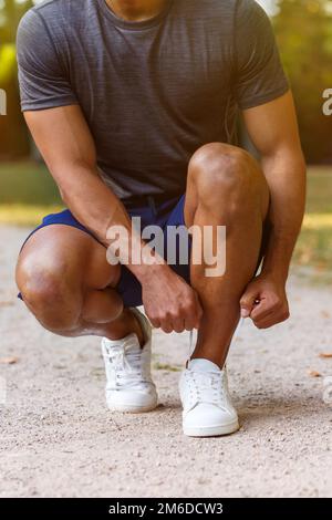 Allacciatura lacci scarpe scarpe runner giovane uomo pronto preparazione start formato ritratto running sport Foto Stock