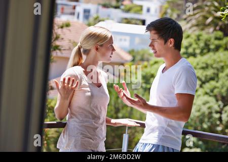 Discutiamo e combattiamo, ma stasera bene essere d'accordo. una giovane coppia che ha un argomento sul balcone della loro casa. Foto Stock