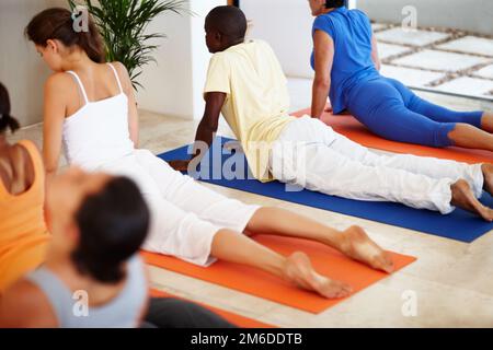 Scarico della sollecitazione. Un gruppo di persone che eseguono una routine in una lezione di yoga. Foto Stock