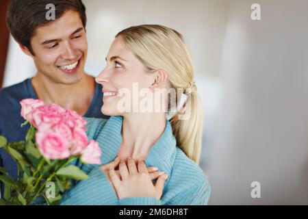 Il loro amore è in fiore. un giovane affettuoso che dona alla sua bella giovane moglie un bouquet di rose rosa. Foto Stock