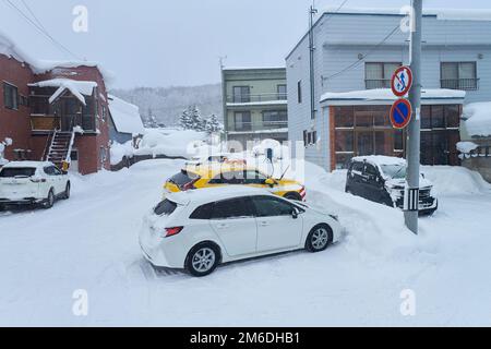 Hokkaido, Giappone - 19 dicembre 2022: Strada coperta di neve di fronte al parcheggio di casa a Hokkaido, Giappone Foto Stock