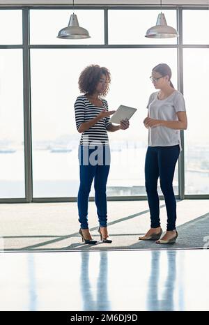 Posso ottenere un rapido ok su questo. le colleghe parlano in piedi davanti a una finestra in un ufficio. Foto Stock