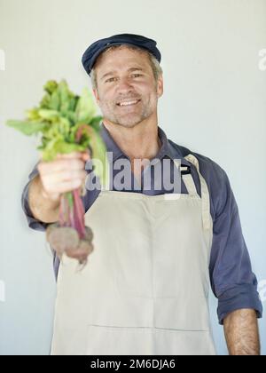 Dovreste provare il nostro. Un uomo maturo che tiene un mazzo di barbabietole. Foto Stock