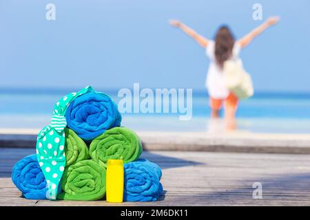 Spiaggia e accessori estate concetto - asciugamani colorati, costume da bagno e sfondo sunsblock bella donna Foto Stock