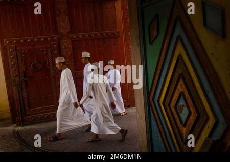 Giovani uomini Omani che indossano abiti arabi tradizionali nel suk di Nizwa, Oman, Foto Stock