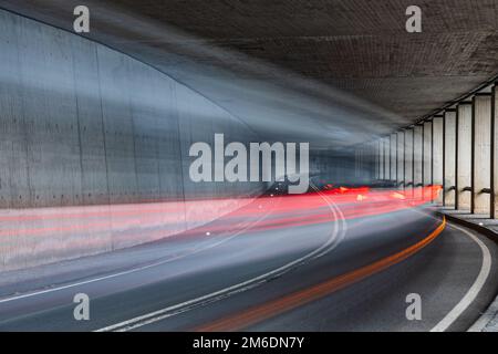 Sfocata auto rossa con luci posteriori a una guida veloce attraverso il tunnel - una lunga esposizione Foto Stock