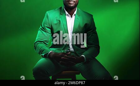 Moda, abito e uomo nero modello con un abito formale seduto su una sedia mentre si posa in uno studio. Elegante, trendy e africano maschio nel lusso Foto Stock