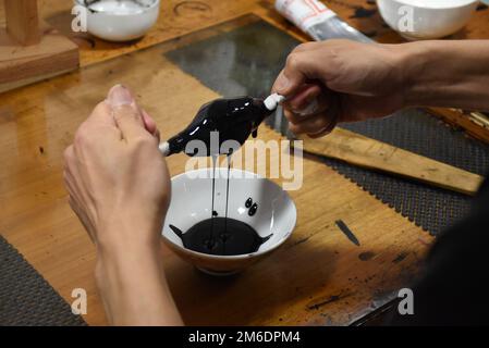 Filtrazione della lacca giapponese urushi per rimuovere le particelle di polvere - preparazione della materia prima per creare lacceria tradizionale luxurious e lucida Foto Stock