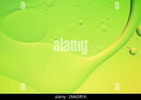 Gocce d'olio in acqua. Immagine astratta con pattern psichedelico sfocato colore verde e giallo sfumato. Foto Stock