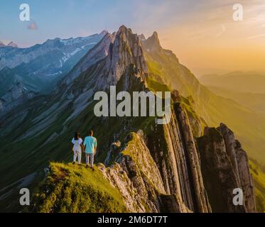 Coppia al siepe di una montagna che guarda il tramonto, Schaeffler cresta di montagna swiss Alpstein, Appenzell Svizzera, un ripido cresta della maestosa cima Schaeffler, Foto Stock