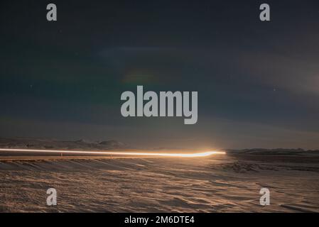 Auto percorsi luce di notte su una strada in Islanda Foto Stock