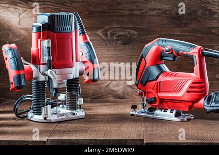 utensili elettrici manuali sega a filo rosso e velocità variabile potenza piccola trampolino fresatrice mini legno portatile router su legno vintage backgro Foto Stock