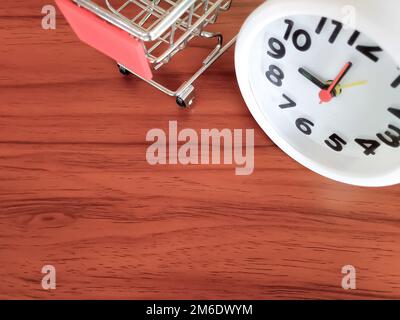 Un orologio bianco e un mini carrello posti su un tavolo di legno marrone. Commercio Di Affari Foto Stock