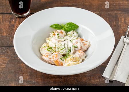 diversi tipi di pelmeni o gnocchi russi in piatto bianco su fondo in legno Foto Stock