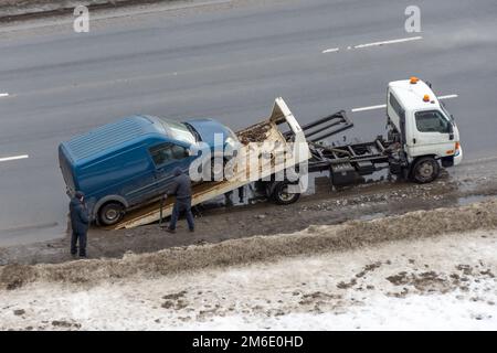 Rottura dell'auto e traino su strada innevata. Strada invernale coperta di neve su strada, ghiacciata Foto Stock