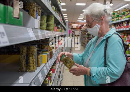 Donna anziana con negozi di maschere facciali nel supermercato Foto Stock