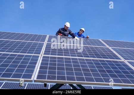 Tecnico di manutenzione presso lo stand di un'azienda agricola a pantografo, ispezione del pannello solare e riparazione Foto Stock