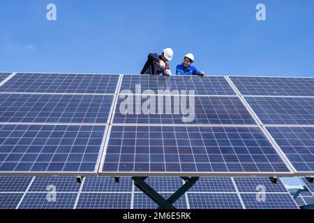 Tecnico di manutenzione presso lo stand di un'azienda agricola a pantografo, ispezione del pannello solare e riparazione Foto Stock