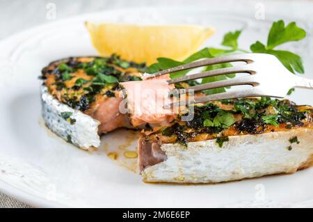 Provate una deliziosa bistecca di salmone. Un pezzo di pesce rosso su una forchetta Foto Stock