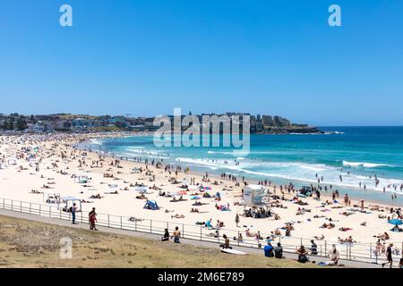 Estate 2023, Bondi Beach Sydney in una giornata di estate con cielo blu chiaro, spiaggia piena e affollata con persone che prendono il sole e nuotano, Sydney, NSW, Australia Foto Stock