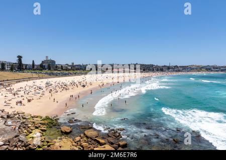 Estate 2023, Bondi Beach Sydney in una giornata di estate con cielo blu chiaro, spiaggia piena e affollata con persone che prendono il sole e nuotano, Sydney, NSW, Australia Foto Stock