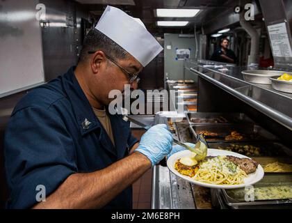 OCEANO INDIANO (26 aprile 2022) Specialista culinario 1st Classe Robert Rademaker prepara un pasto durante una cena celebrativa del mese di compleanno di aprile sui ponti disordine a bordo del cacciatorpediniere missilistico guidato USS Gridley (DDG 101) nell'Oceano Indiano, 26 aprile. Gridley è dislocato nell'area operativa della flotta degli Stati Uniti 5th per garantire la sicurezza e la stabilità marittima nella regione del Medio Oriente. Foto Stock