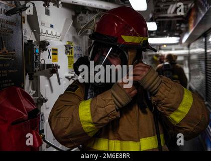 OCEANO INDIANO (26 aprile 2022) Specialista del personale 1st Classe Reggie Reyes indossa un casco antincendio durante un'esercitazione di controllo dei danni a bordo del cacciatorpediniere missilistico guidato USS Gridley (DDG 101) nell'Oceano Indiano, 26 aprile. Gridley è dislocato nell'area operativa della flotta degli Stati Uniti 5th per garantire la sicurezza e la stabilità marittima nella regione del Medio Oriente. Foto Stock