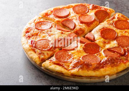 Classica pizza peperoni con salsicce, formaggio fuso e salsa di pomodoro primo piano su tavola di legno. orizzontale Foto Stock