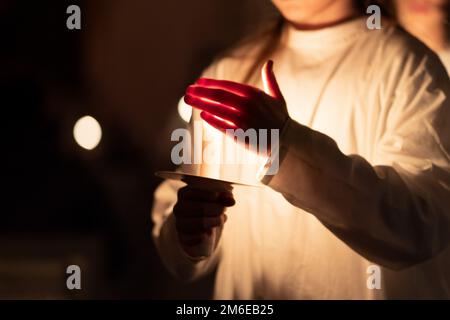 Persone che maneggiano le candele nelle mani. Natale e lucia Foto Stock